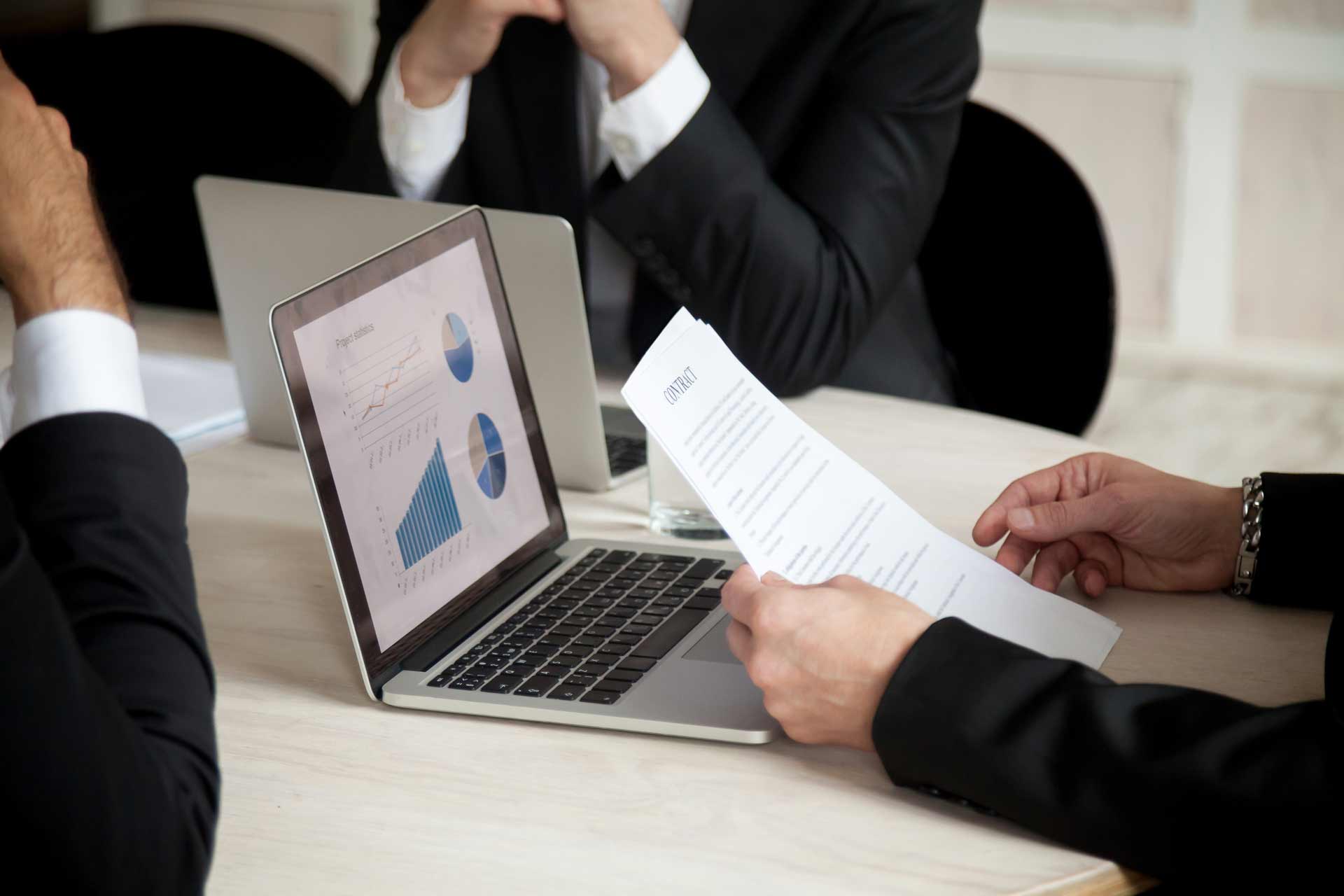 Homem sentando de frente para o notebook em uma sala de reunião