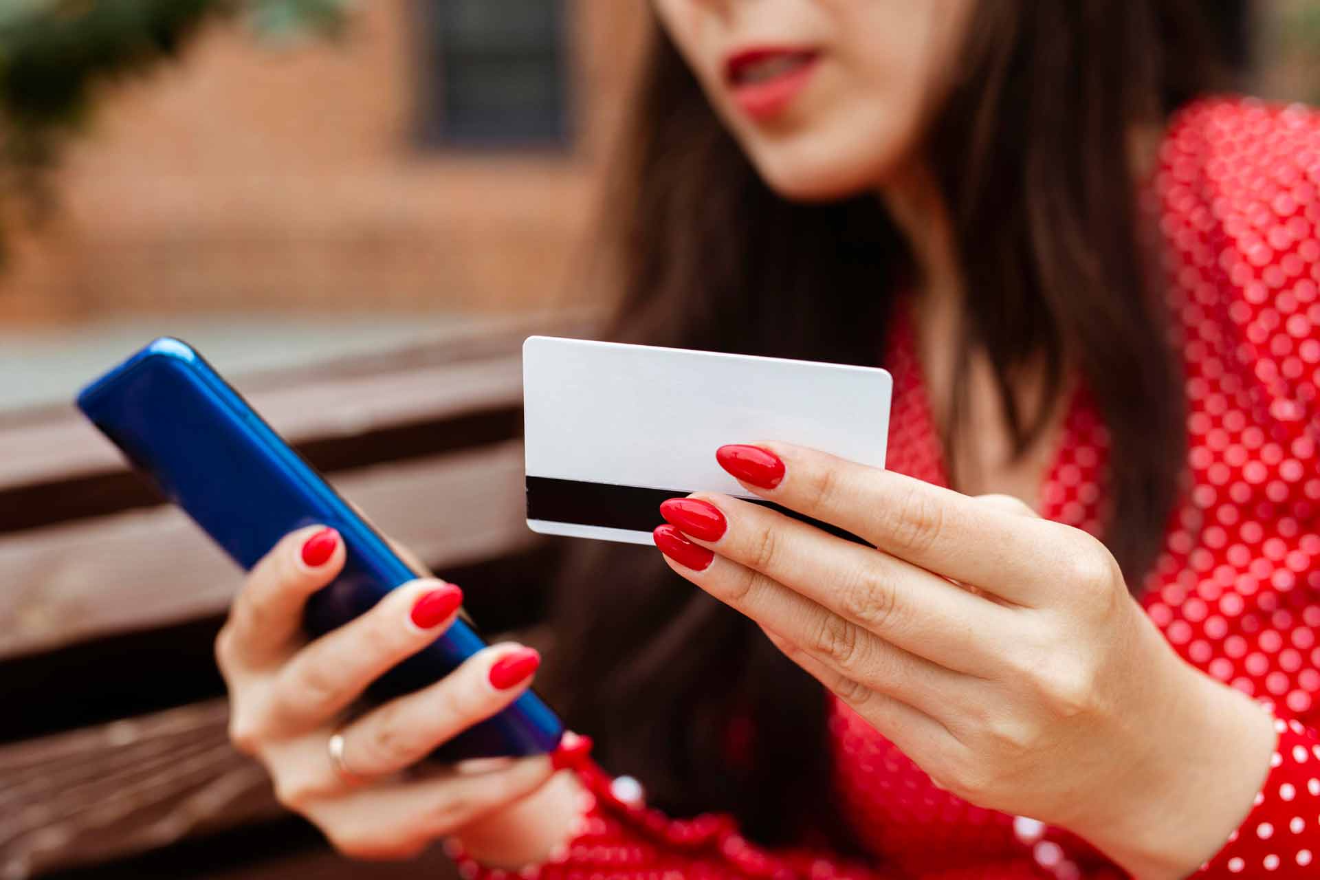 Mulher segurando o celular e o cartão de crédito fazendo uma compra online